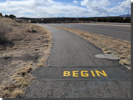 [A pedestrian path with BEGIN written across it in yellow tape]