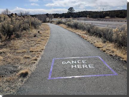 [DANCE HERE written in purple tape on a pedestrian path]