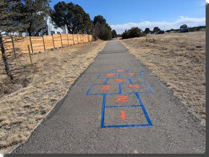 [a hopscotch made of blue and orange tape on a pedestrian path]