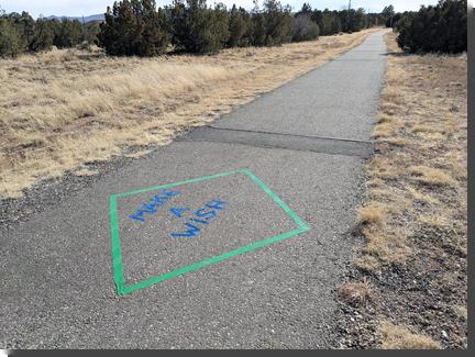 [MAKE A WISH on a pedestrian path, done in blue tape surrounded by a green tape diamond]