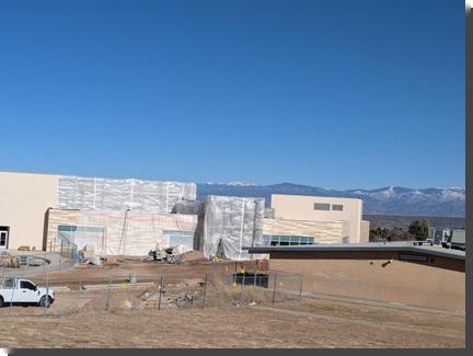 [A school building under construction, covered with clear plastic wrap]