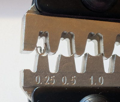 [Side view of the end of the jaws of a crimp tool, holding the piece to be crimped. The opening is marked 0.25]
