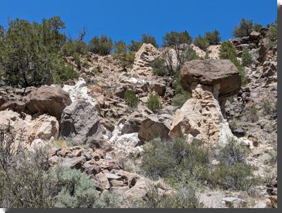 [Multicolored tuff and basalt rocks, including a hoodoo with a tent of tuff supporting a large basalt boulder]