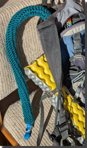 [A pack to hold a Camelbak, with the hose covered by a thick, dark green knitted tube]