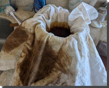 [a shirt that appears to be tie-dyed, but only in brown dye, is draped over a pitcher to be used as a filter for making coffee]