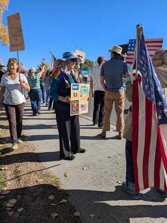 [a protester holds a sign: NO KINGS. NO IDIOTS EITHER.]