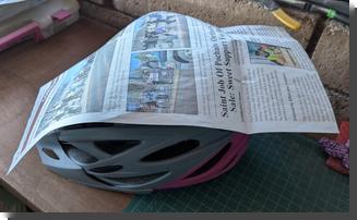 [a piece of newspaper draped over a bike helmet]