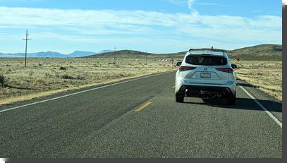 [Long line of cars, as far as the eye can see, along a road curving off into the distance]