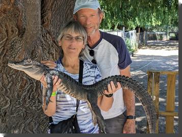 [The author holding a baby alligator, with husband standing behind her]